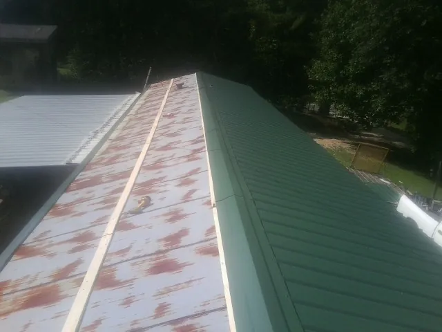 Old rusted panels beside newly installed green metal roofing — Wind Damage Roof Repair by Roofing Brothers in Radiant