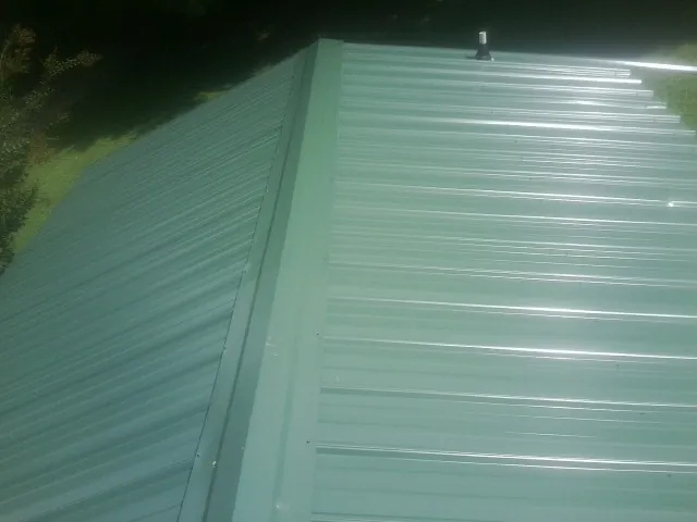 New green metal panels meeting at the ridge of a roof — Flat Roof Repair work by our crew in Radiant