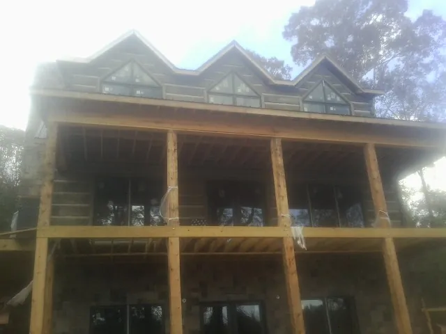 Dormers and porch framing on a large log home under construction — Roof Coating work by our crew in Radiant