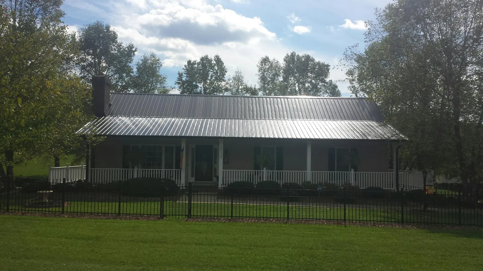 Gray metal roof on a brick ranch with a full width front porch — Gutter Guard Installation work by our crew in Radiant
