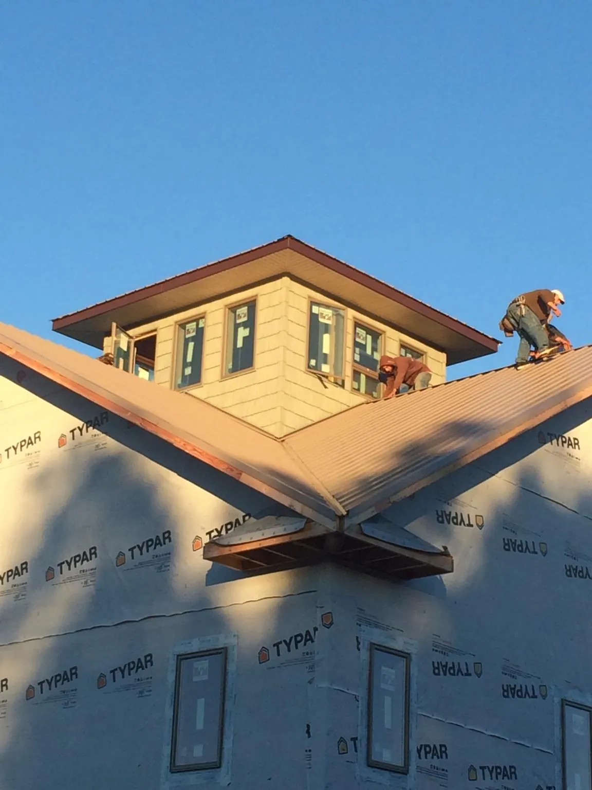 Roofers working around a rooftop cupola on a new metal roof at sunset — Roof Waterproofing in Radiant by Roofing Brothers